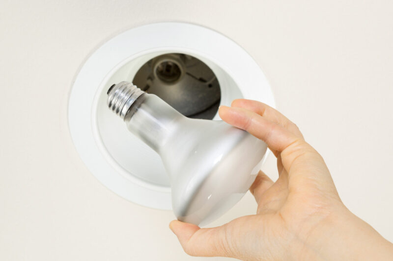 inserting incandescent light bulb into recessed light