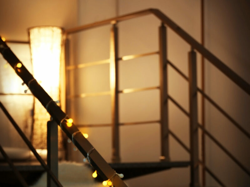 staircase with floor lamp on platform and string lights